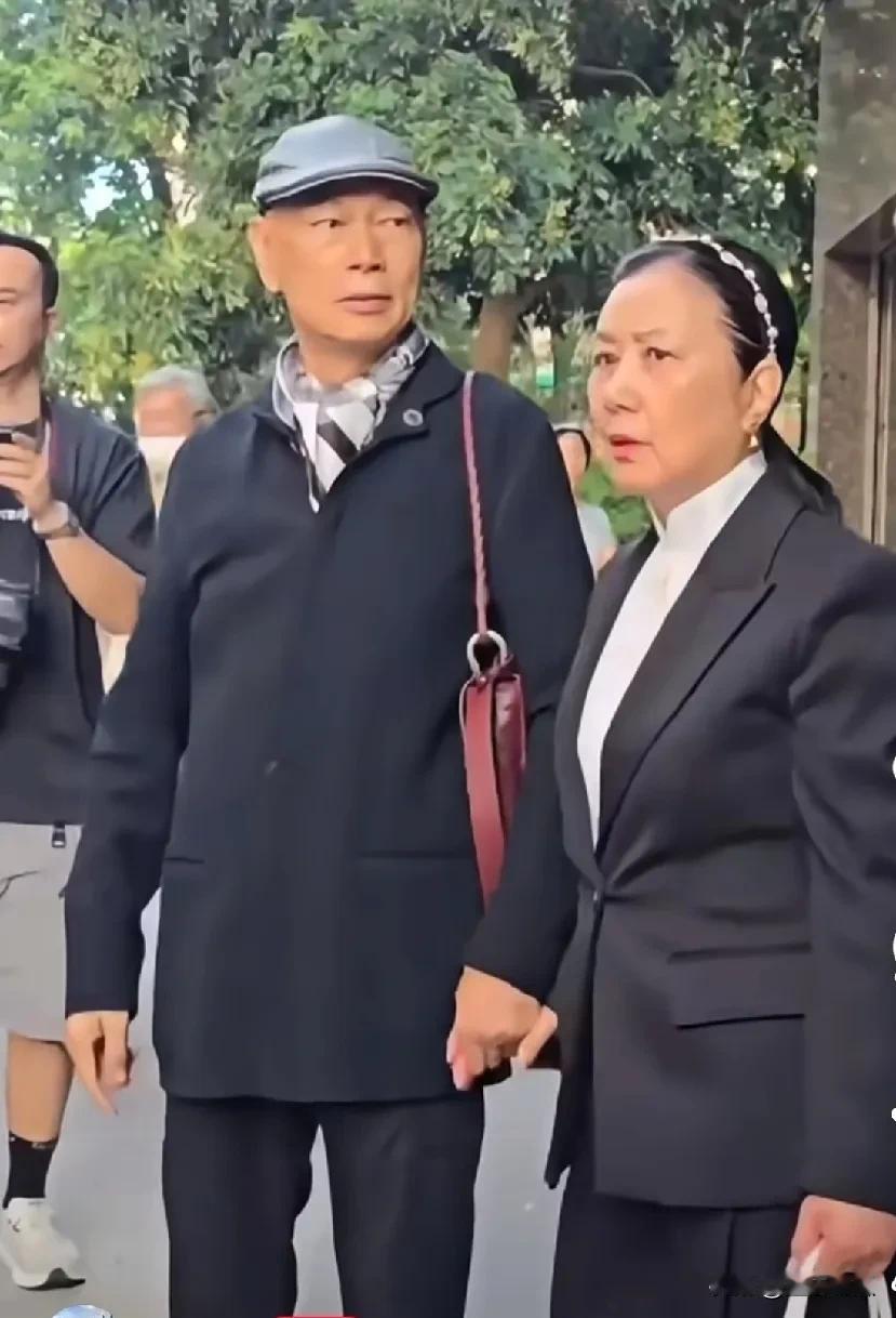 这便是汪明荃和罗家英真实的模样，两人手挽手漫步在大街上。身着朴素的衣物，素颜朝天