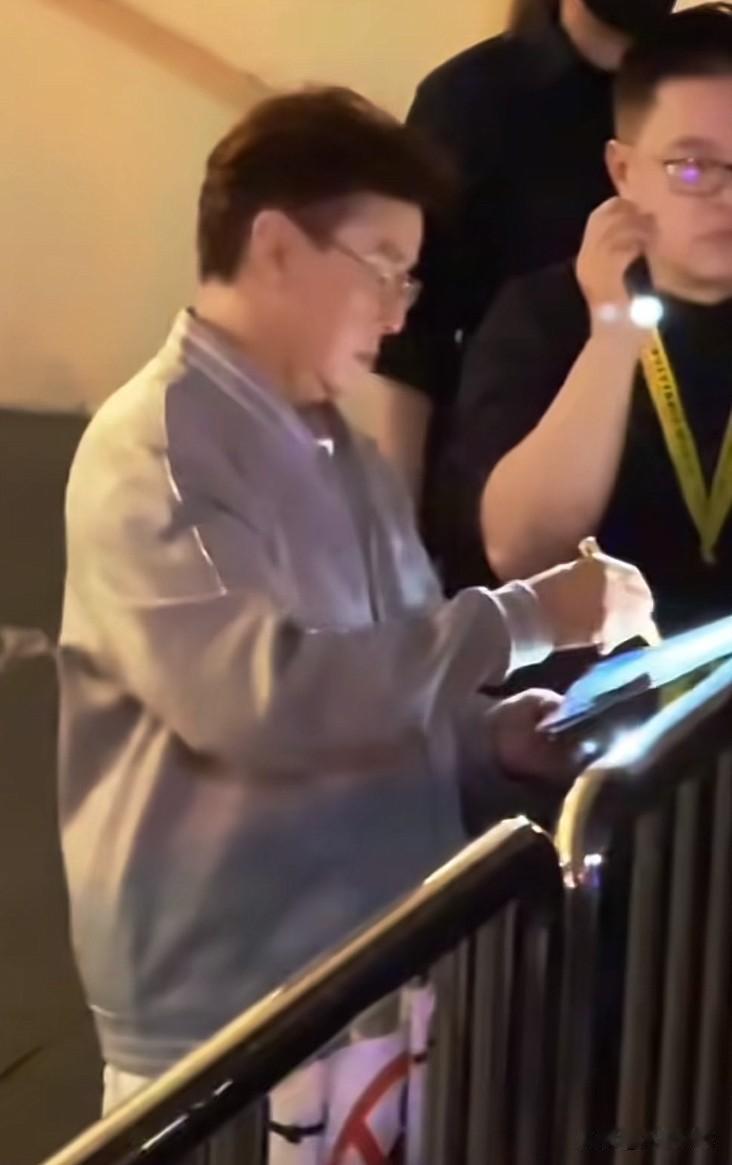 晚上一点了，开完尾场演唱会的香港歌星谭咏麟走出体育馆，手里拿着签字笔走向粉丝群给