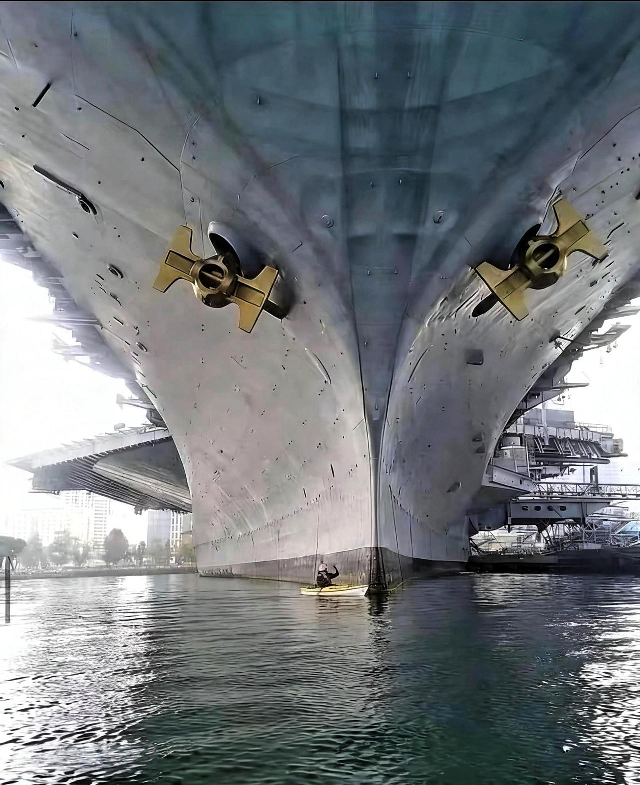 停泊的航母与一艘小船的比例。美军林肯号航空母舰到底有多大？且看这张照片，一艘小