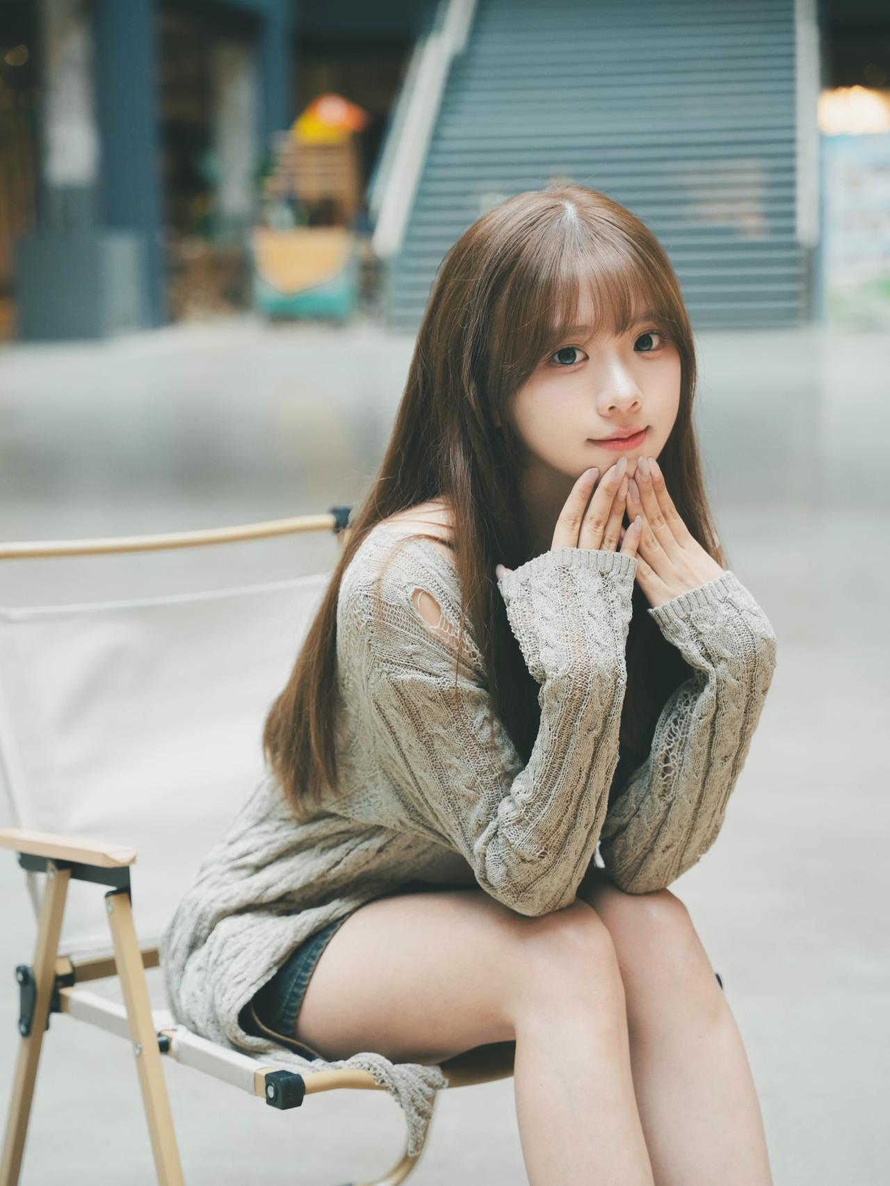 温柔少女，坐在折叠椅上，微笑着，背景模糊，氛围温馨。