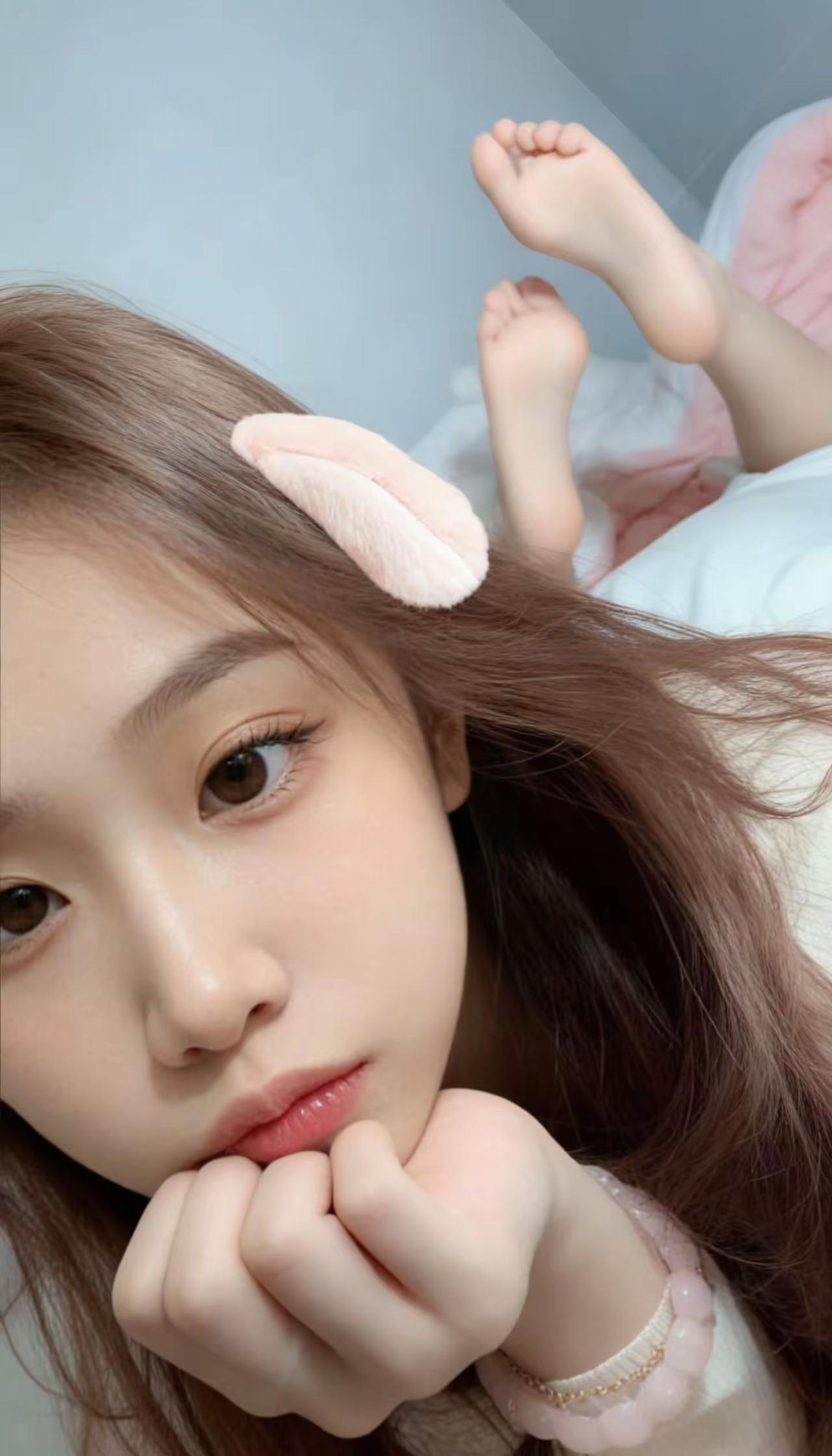 粉粉的兔耳发夹别在蓬松的棕发上，软乎乎的小手托着腮，连脚丫都跟着慵懒翘起，是窝在