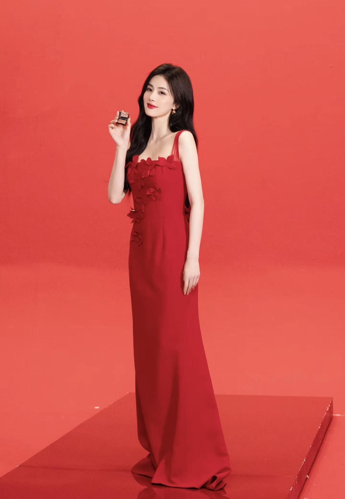 一袭正红吊带长裙惊艳亮相，缎面材质衬得肌肤莹润透亮，纤细肩带勾勒出优美肩颈线，白