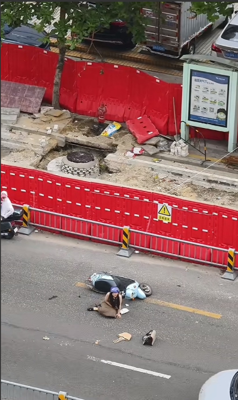 广东，女子骑车与别人发生交通事故摔倒在地上疼痛不已，看着被甩在不远处的小猫咪受惊