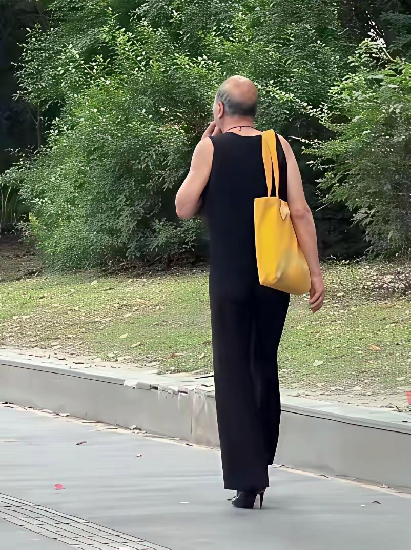 路上偶遇这位大爷，一身黑色无袖长裙，脚踩高跟鞋，还挎着亮眼黄包，穿搭格外吸睛。
