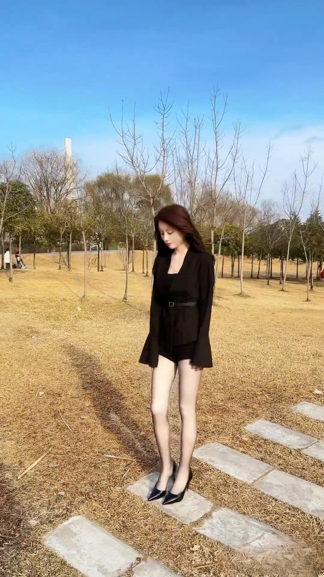 秋日漫步，黑裙与落叶相映成趣。