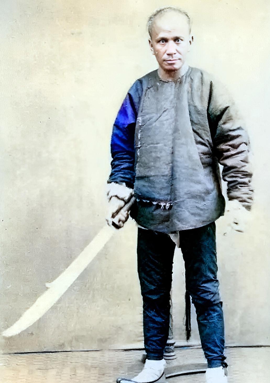 晚清一名凶神恶煞的男子手持一把大刀。这名男子虽然个头不高，但气势很足。他眉骨很高