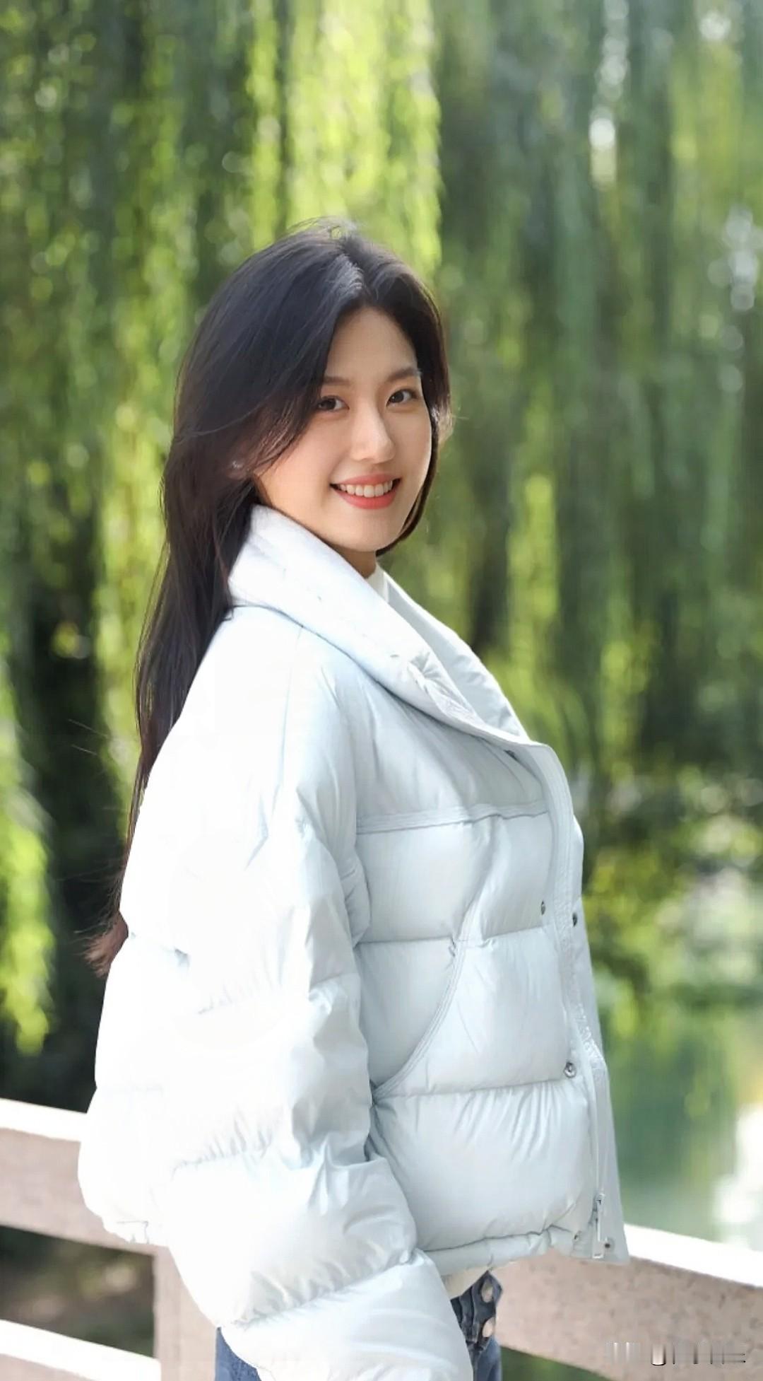 冬日暖阳下，白衣少女笑靥如花，绿意盎然的背景，宛如一幅温馨的画卷。手机每天随手拍