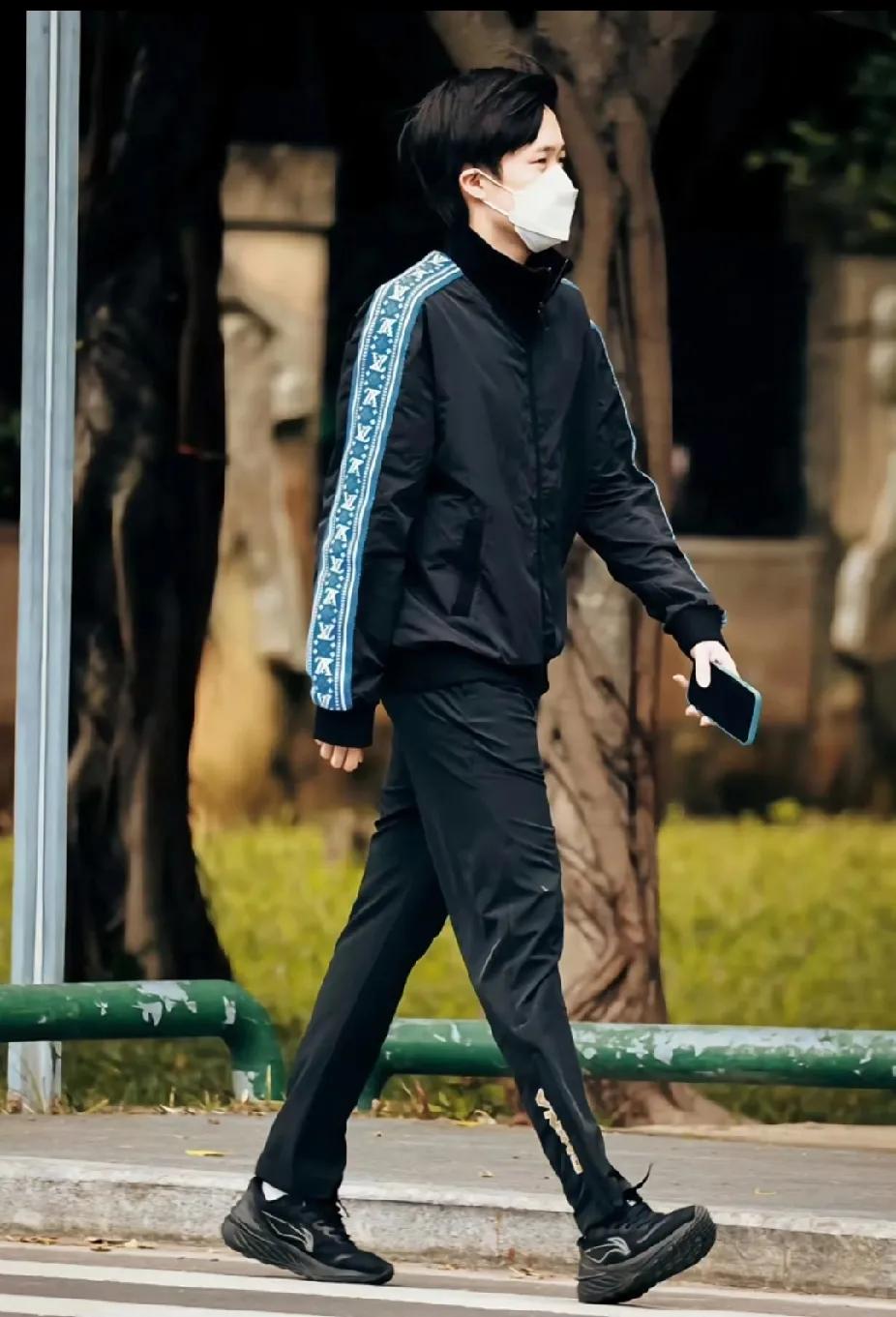 刷视频时偶然刷到一位帅哥！他一身黑色运动穿搭超有型，外套侧边蓝纹很吸睛。戴着口罩