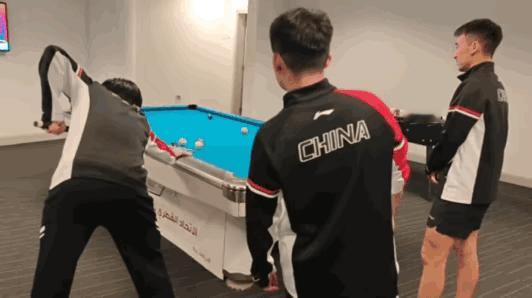 结束了训练，大家都在等待班车发车，旁边有台球桌，王楚钦抓紧跑过去，着急忙活的