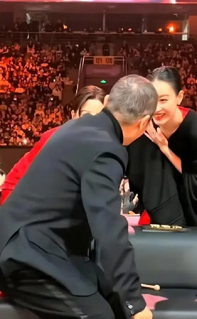 倪妮在威尼斯电影节后台蹲着给辛芷蕾拍照，手机都快贴地了。画面里辛芷蕾穿着银色