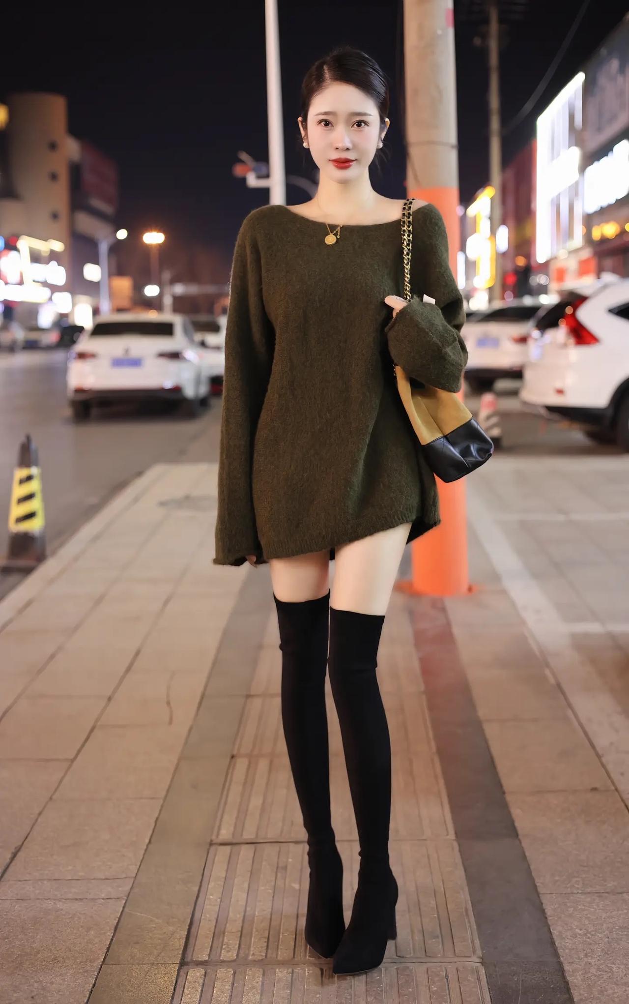 都市夜色下的时尚穿搭，黑色靴子与绿色毛衣的完美搭配，尽显优雅与自信