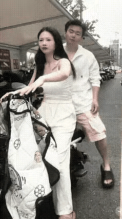 一对夫妻骑着电动车准备出门，丈夫坐在后座，满心温情，想着搂一下妻子的腰，靠着爱人