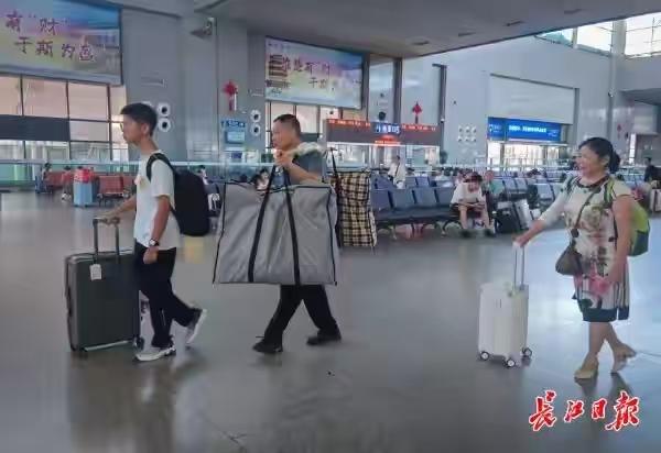 湖北黄冈的一对夫妻，送考上上海大学的儿子去报到。没有行李箱，父亲就靠着一根扁担，
