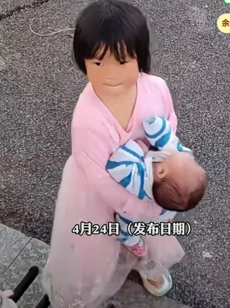 小女孩抱着婴儿独自在外边玩，一旁女子看到后很是担心，女子说太危险了，也不知如何