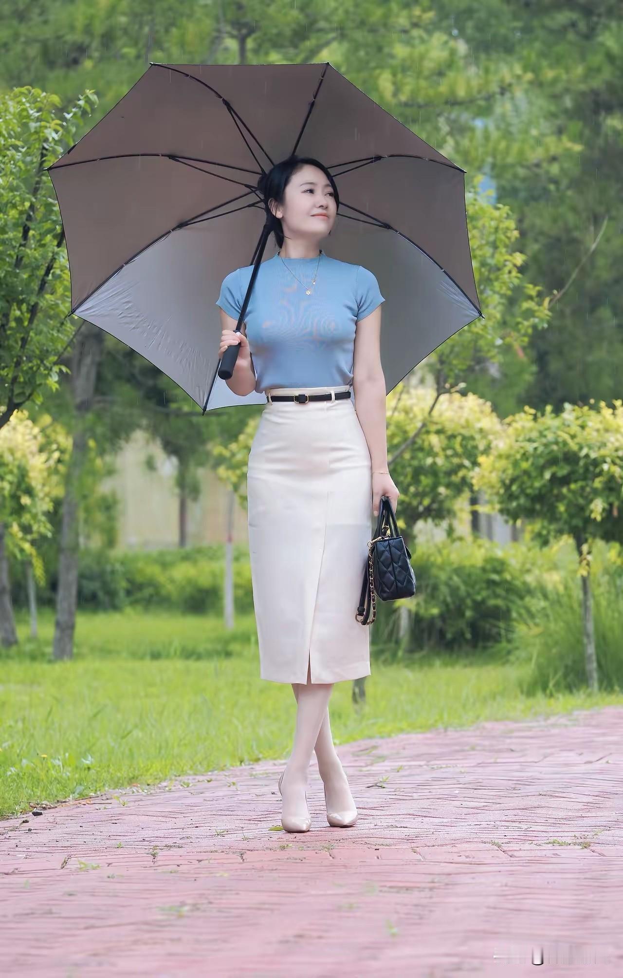 雨中漫步，撑伞漫步在绿意盎然的公园小径上，清新自然。