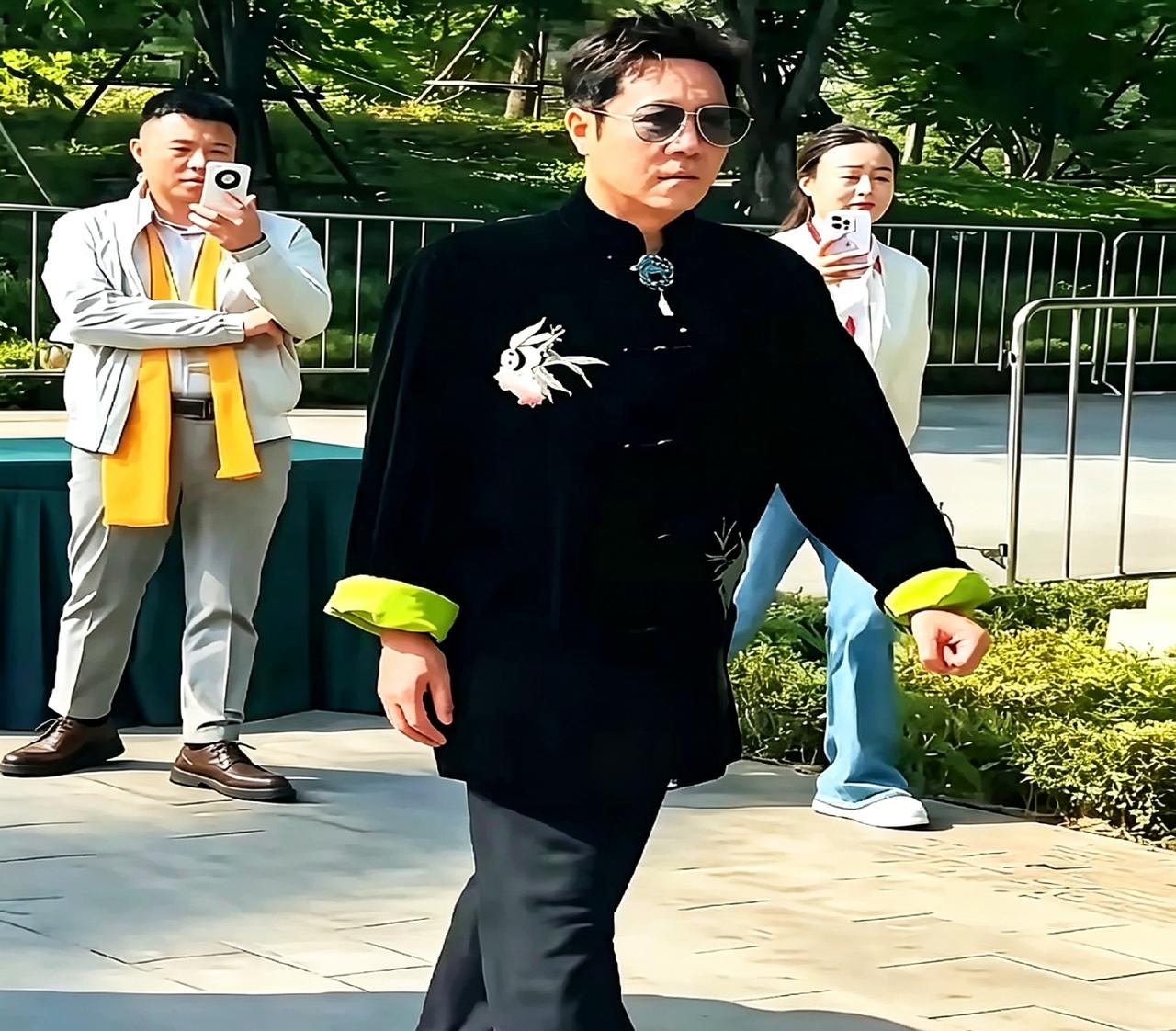 蔡国庆老师这精气神绝了！戴墨镜走路带风，身穿黑底新中式，袖口那抹亮黄特别抢眼。胸
