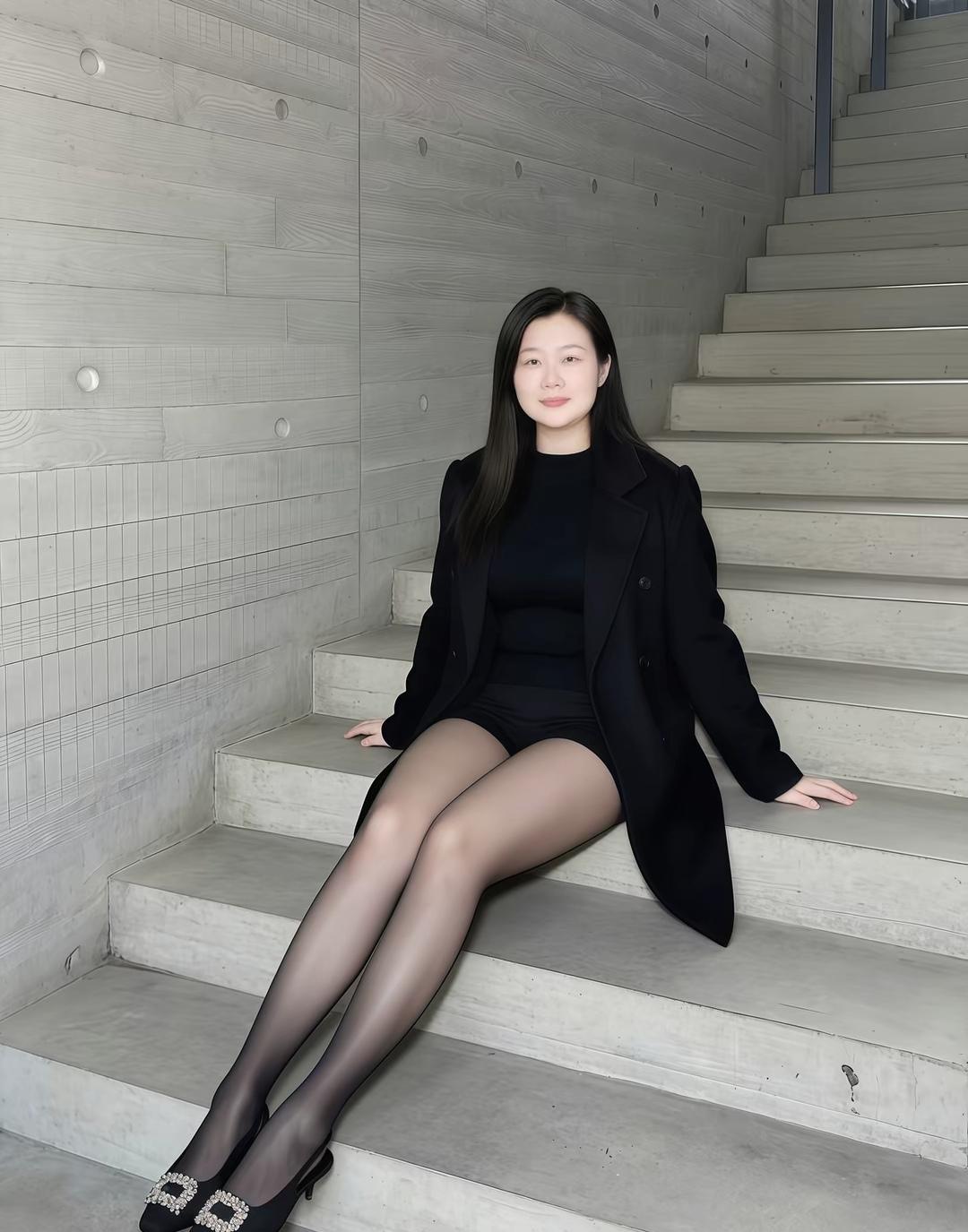 优雅黑衣少女，静坐楼梯间，尽显都市风范。