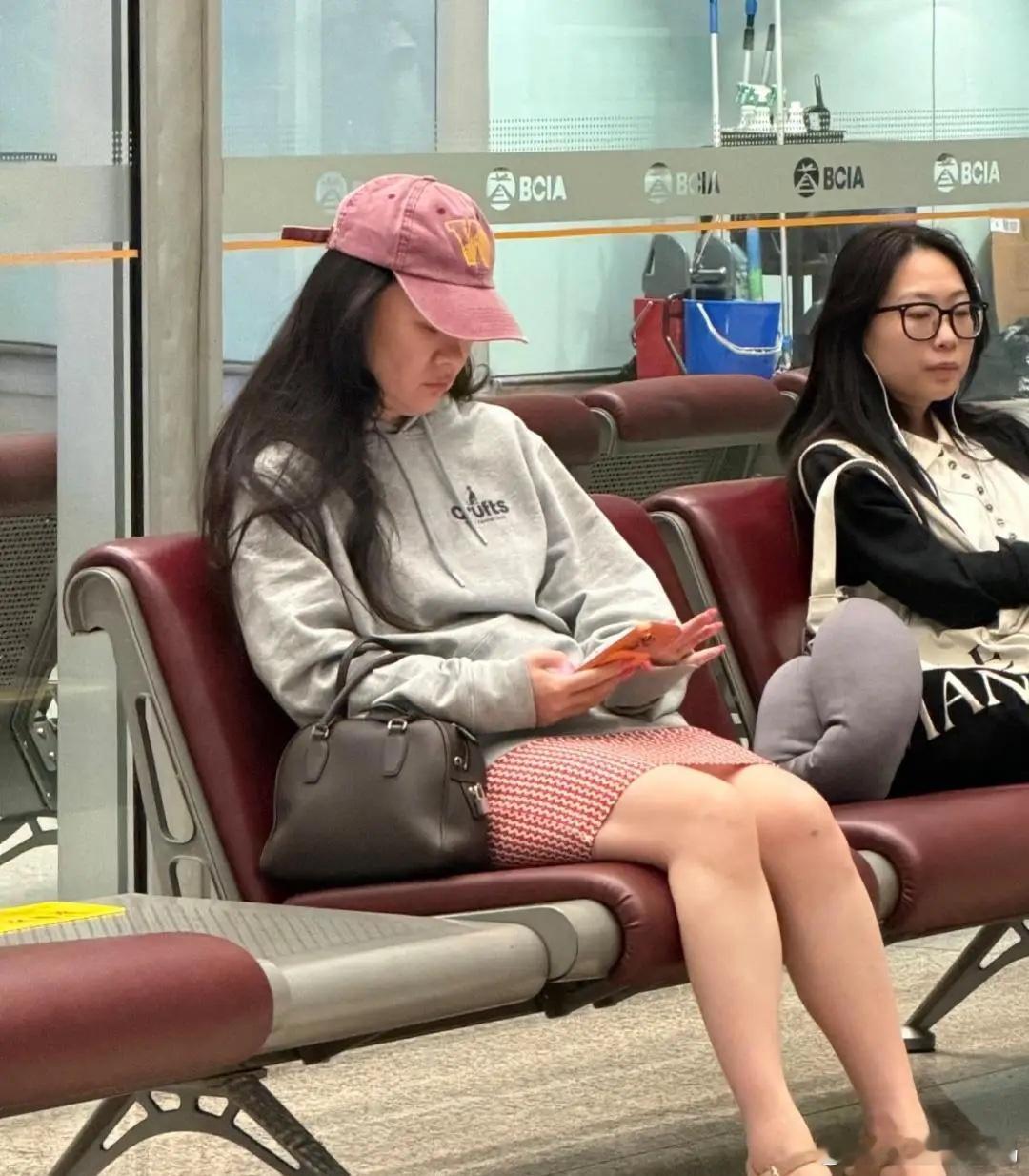 46岁霍思燕和13岁儿子嗯哼现身机场，她打扮休闲，她穿着卫衣和一条小短裙，坐在休