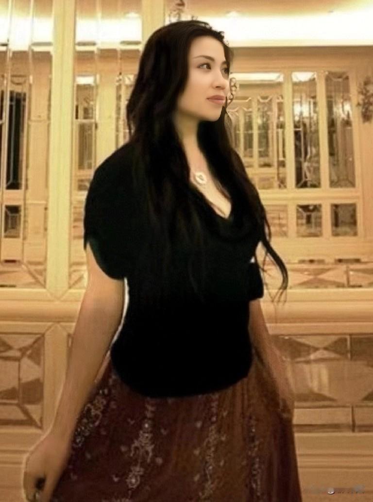 张也褪去旗袍，换上时尚服装体态仍显温润，依旧优雅知性。黑色卷曲长发披肩，增添典雅