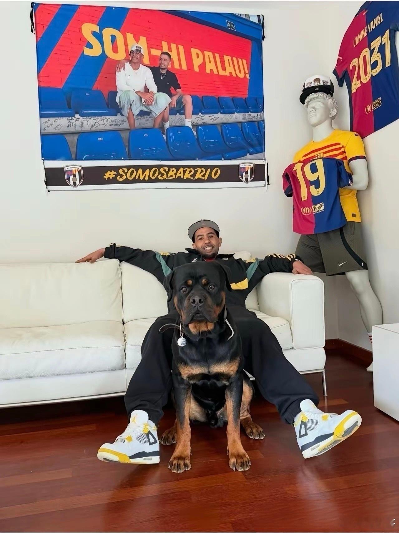 亚马尔的父亲和爱犬同处一室，家中红蓝交织，尽显儿子的足球荣耀。自上次遇袭受伤休养