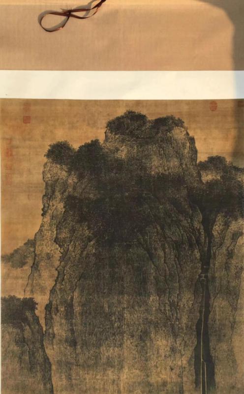 1958年，一位专家正聚精会神地研究一幅古画，突然发现画中树叶里有两个字闪了一下