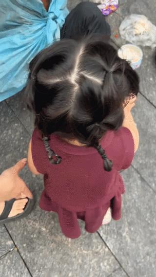 广西玉林街头，一个小女孩手上拿着10块钱要递给一位正在路边乞讨的老爷爷。结果老