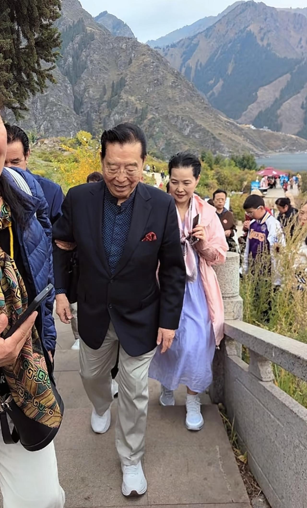 近日，李双江携妻子梦鸽到新疆游玩，夫妻俩现身天山池风景区的画面。86岁的李双