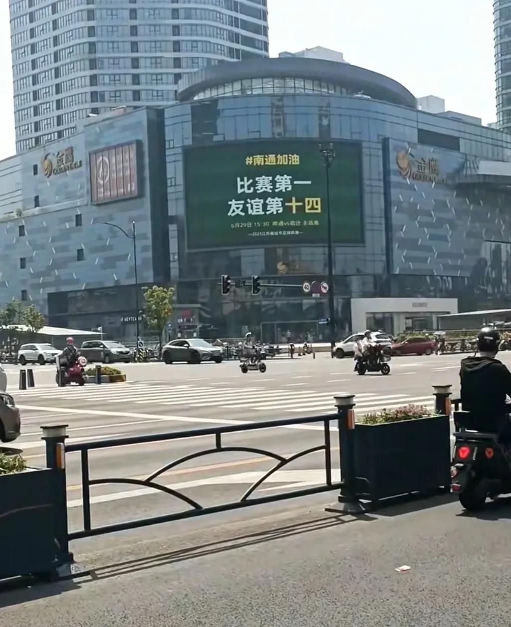 南通街头的大屏幕广告宣传“苏超”，这下也不装了，高考第一，足球第一，该宣传就得宣