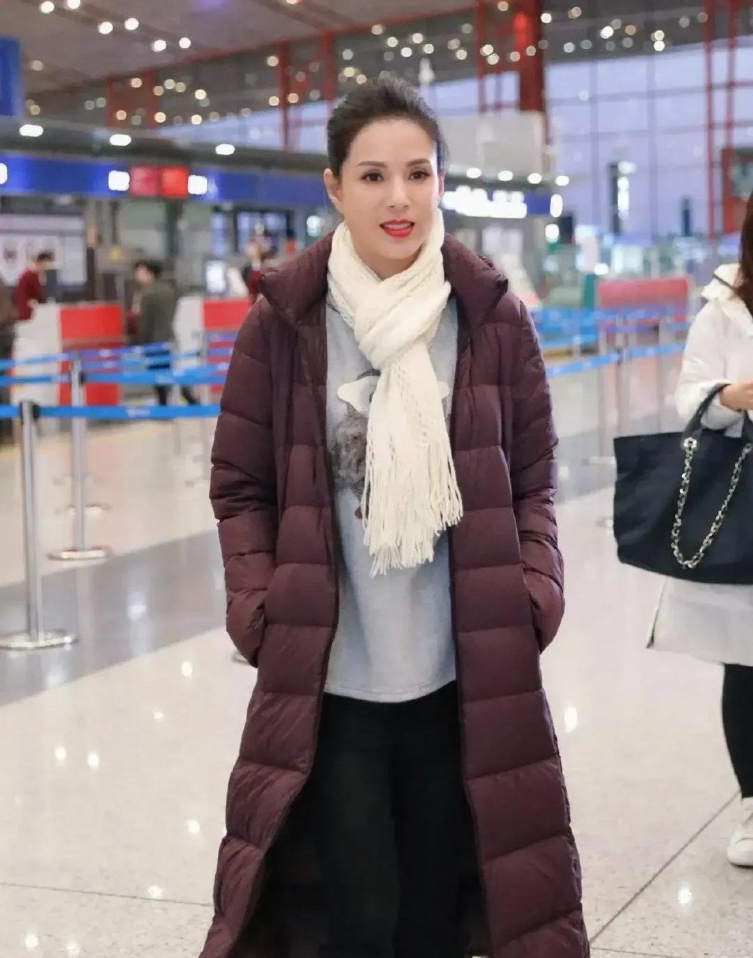58岁李若彤的机场造型太圈粉！棕红色长款羽绒服配灰色卫衣，简约又高级，米白围巾点