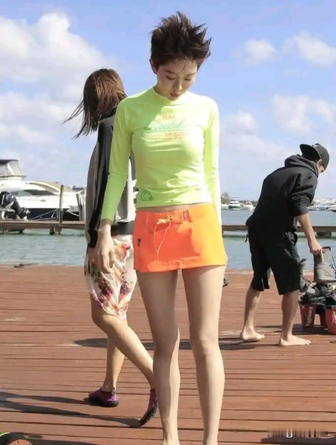 姜妍海边码头这双腿真的绝了！一身荧光绿长袖防晒上衣搭配亮橙色短裤，色彩明艳，