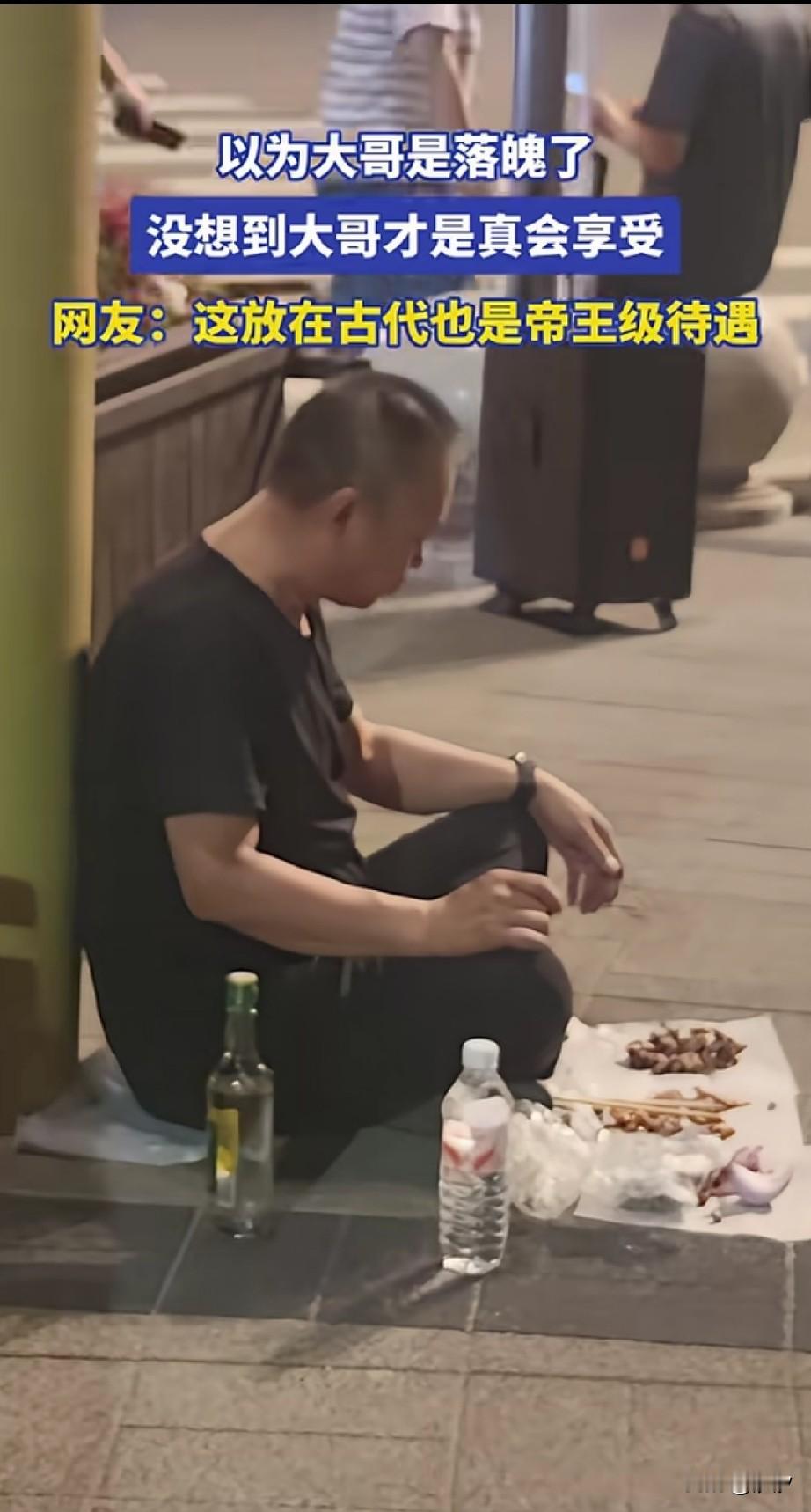 深夜的广场上面，看到一位大叔背靠电线杆，面前摆了花生米和牛肉，旁边是一瓶冰