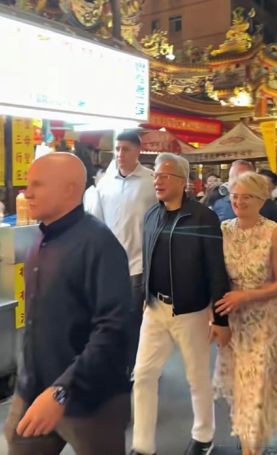 黄仁勋携妻子逛台北夜市时的一幕，妻子一路挽着黄仁勋的手笑靥如花。