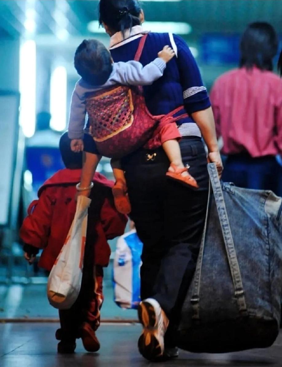 杭州站候车室里，一女子带着三个孩子和大包小包的行李，准备检票坐高铁回家。最大的