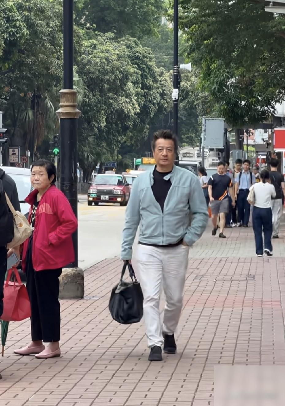 香港街头偶遇77岁的TVB老牌明星石修，独自一人现身街头，手里拎着大包，去给好友