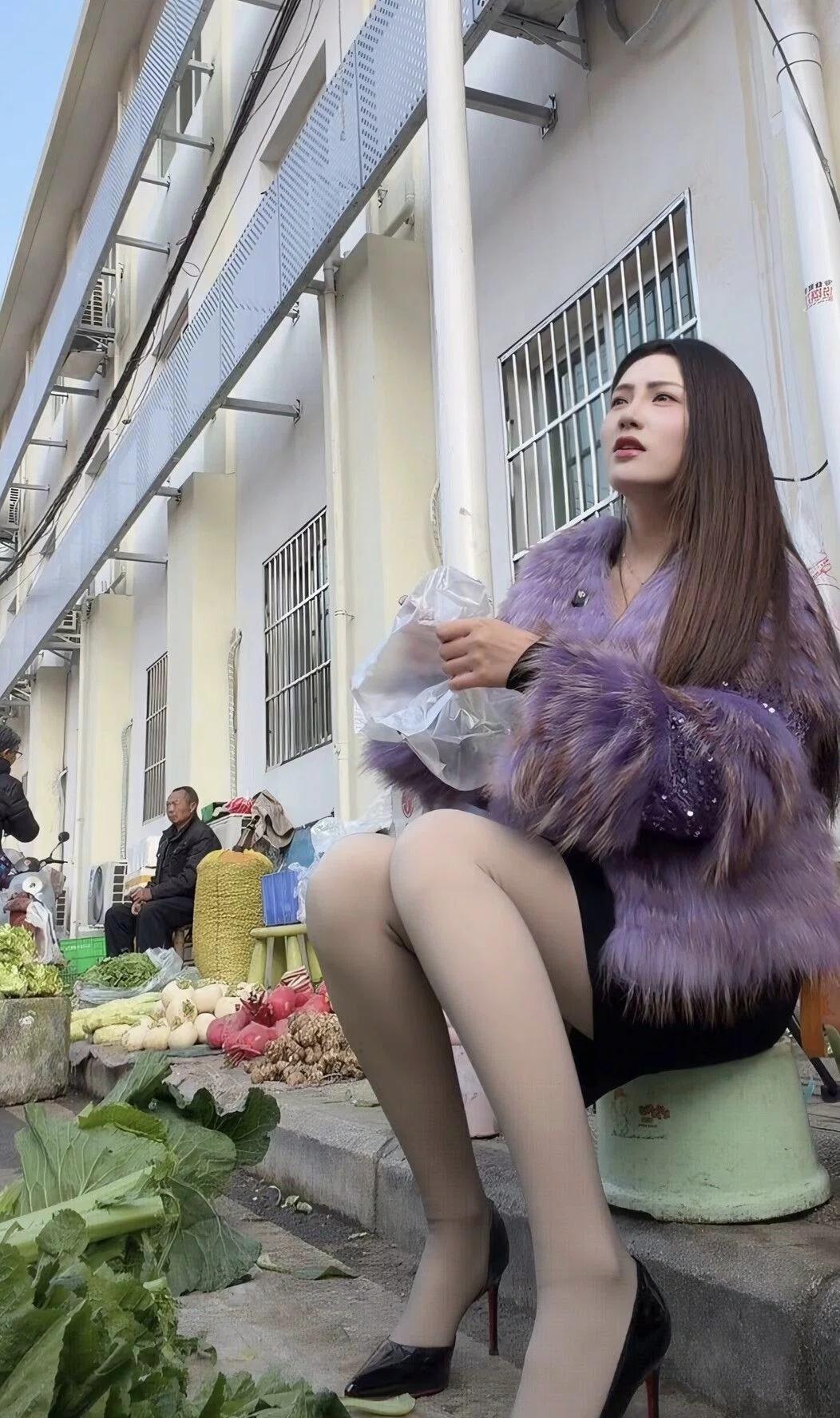 烟火与精致紫貂绒的柔紫裹着身，踩着红底高跟鞋踏入菜市场的喧嚣，青石板路沾着菜