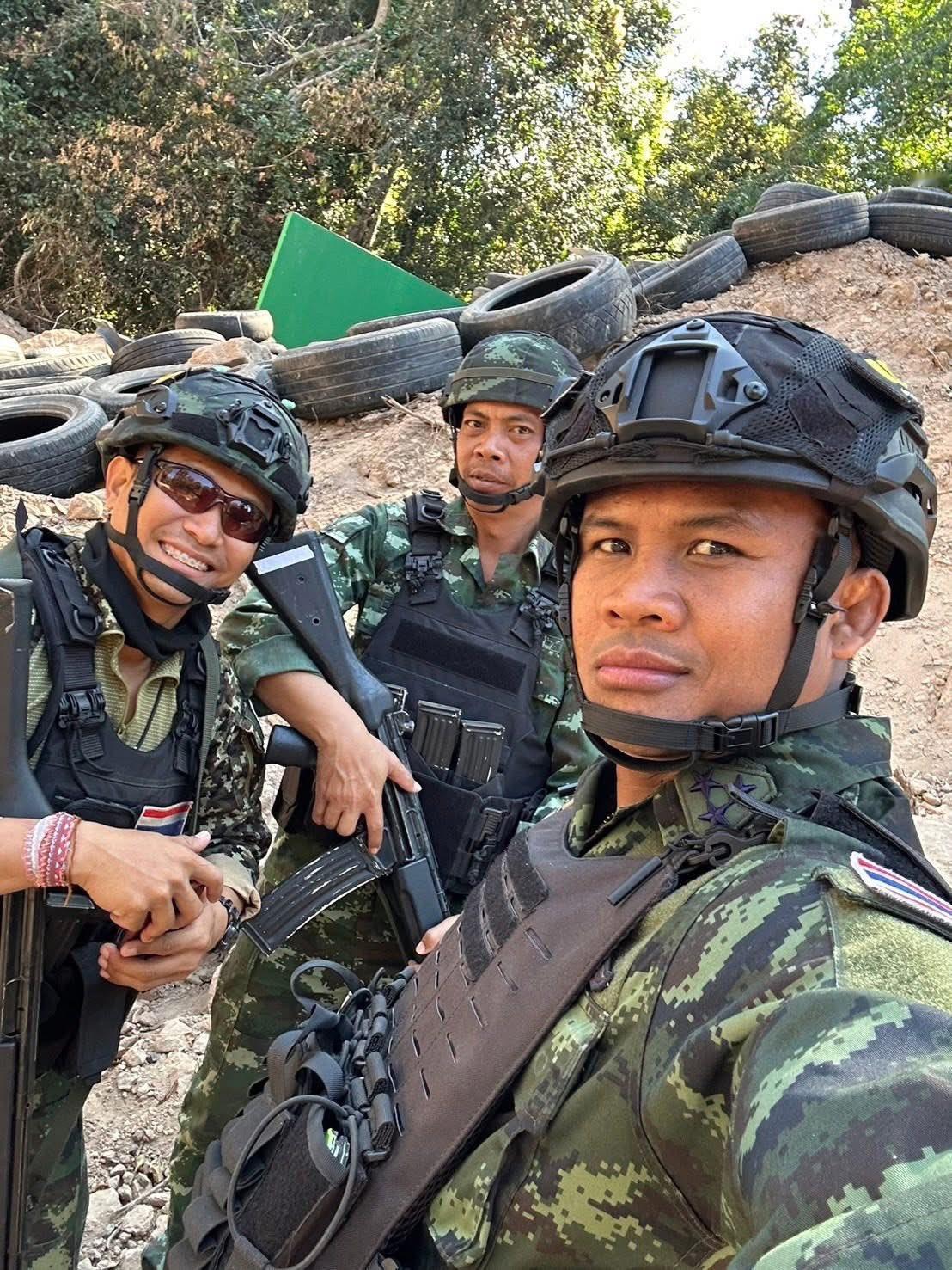 泰拳传奇人物播求·班柴明身穿泰国陆军制服、手持步枪、身处边境哨所轮胎路障旁，并配