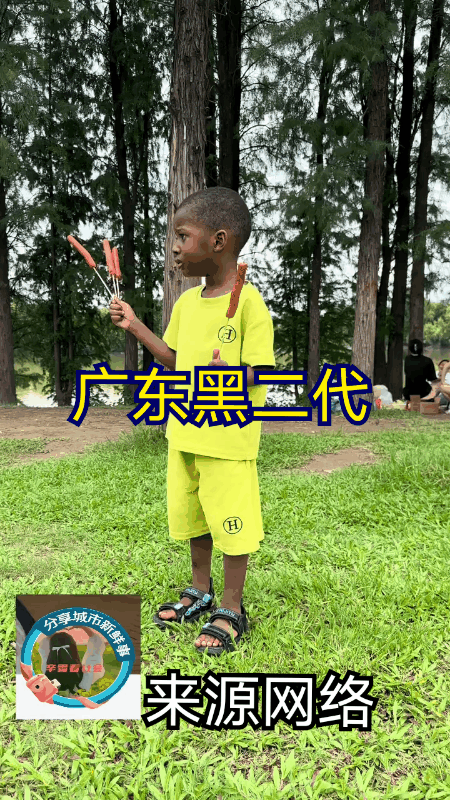广东某地，一个小黑娃正站在景区的湖边吃烤肠，看他吃的真是津津有味。不得不说这些
