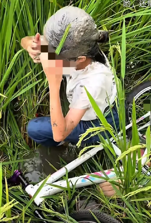 事发广西，一小女孩骑着自行车不小心掉到了路边的稻田里但好在身体没有大碍，路过一好