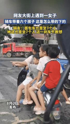 惊呆了！男子开车在路口等红灯，看到旁边的骑电动车的女子，后座带了4个孩子，他想看