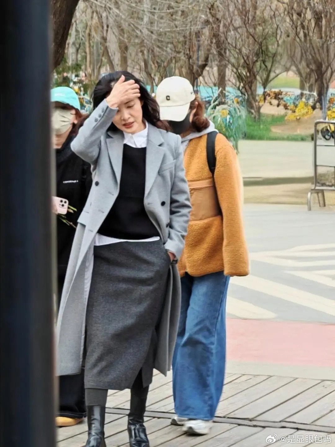 周涛在北京朗园游玩，她穿着灰色大衣和黑色长筒靴，披散着一头长卷发，看起来贵气十足