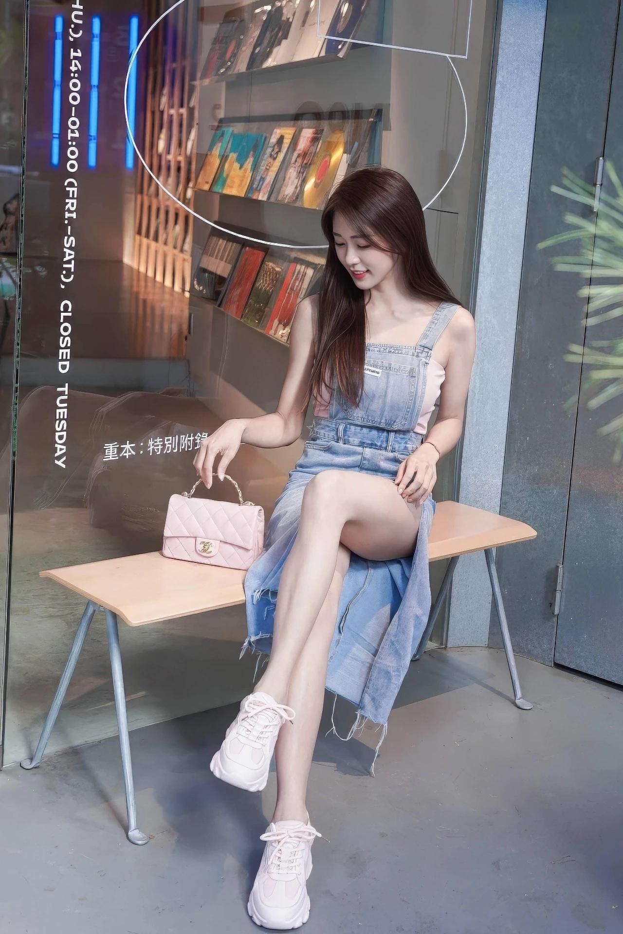 在城市街角的玻璃窗前，牛仔背带裙揉碎了秋日的慵懒，粉粉的包包和运动鞋撞出甜酷氛围