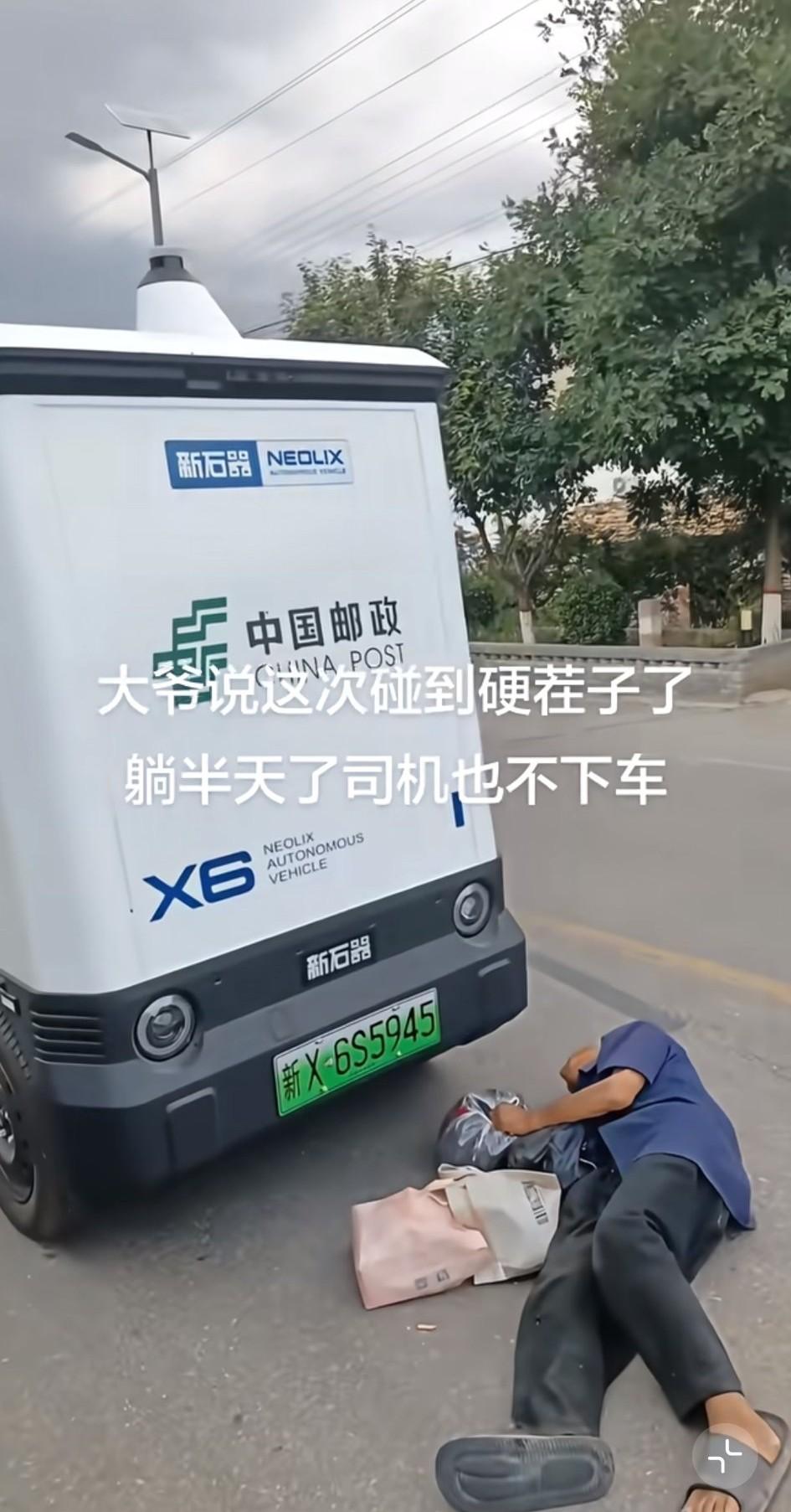 一位大爷躺在一辆无人邮政车的前面，许久过去，也不见司机下车。这时，一位好心人对大