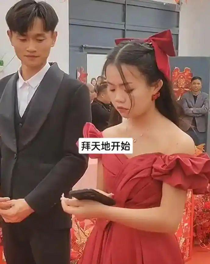婚礼上新娘全程低头玩手机，新郎无奈在一旁小心翼翼的陪着。一对新人结婚当天新娘的
