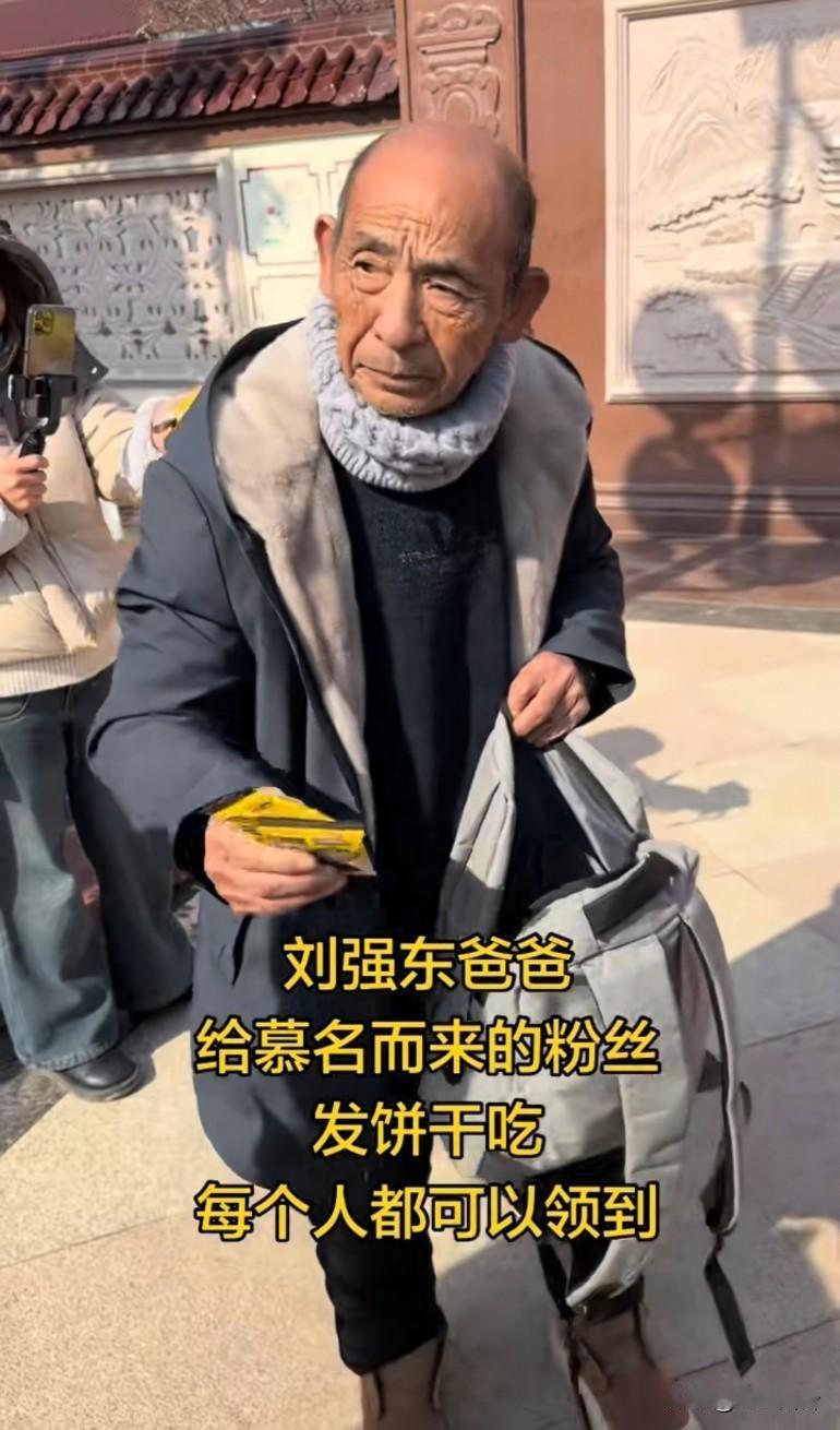 刘强东的爸爸给粉丝发饼干吃，衣着朴素，面相上一看都是地地道道老好人老爷子这衣服