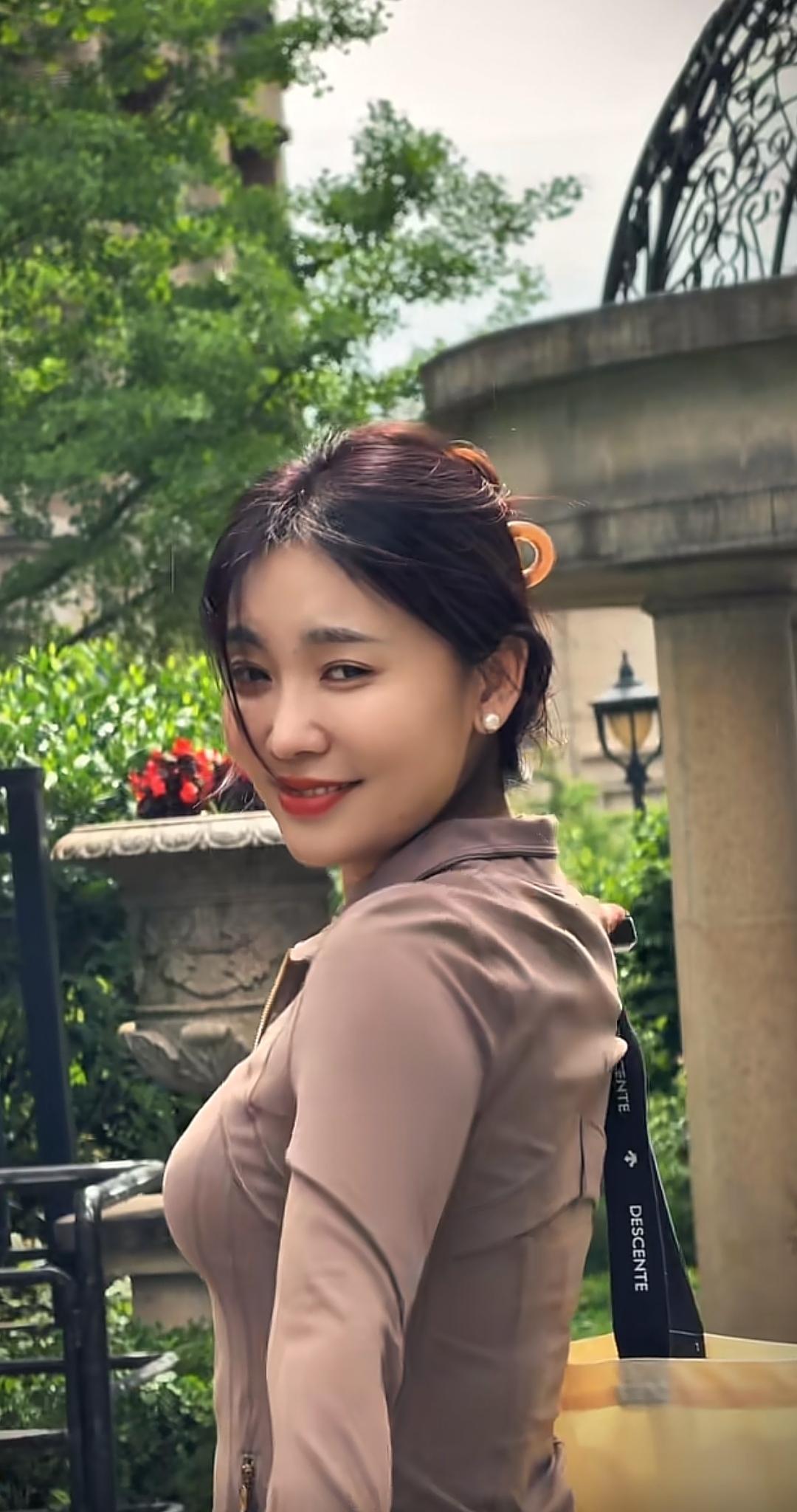 这位优雅气质的女子，笑靥如花地漫步在绿意盎然的庭院中，享受着这份恬静自然。