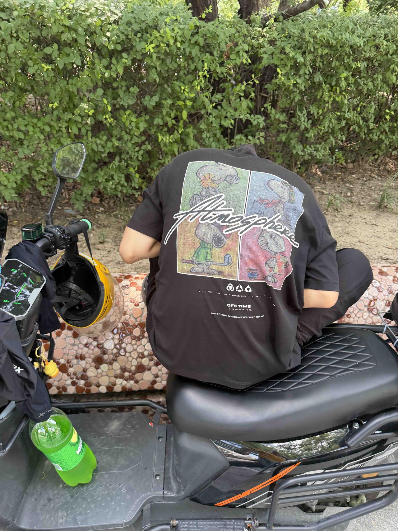 一个人坐在摩托车上，穿着印有卡通图案的T恤。可是脑袋去哪里呢？皮衣摩托卡通t恤