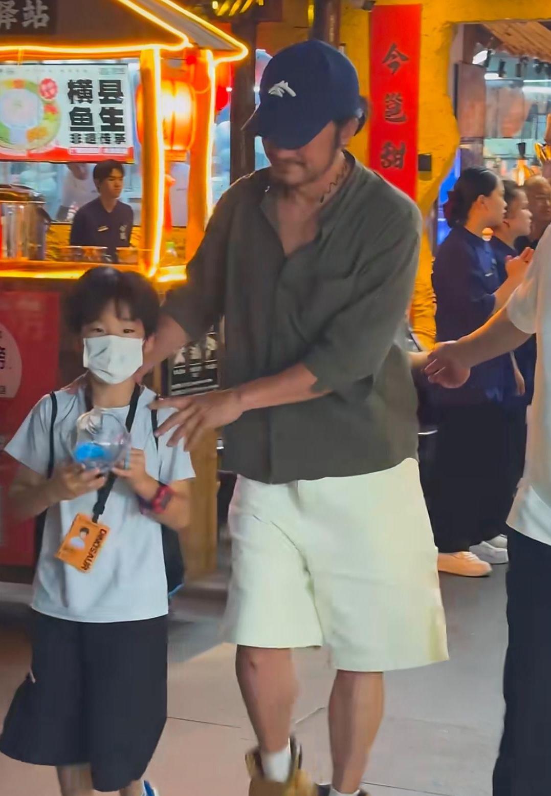 吴京带着小儿子去吃烧烤，他的打扮太一言难尽了，看起来好沧桑。天气这么热，还穿着棉