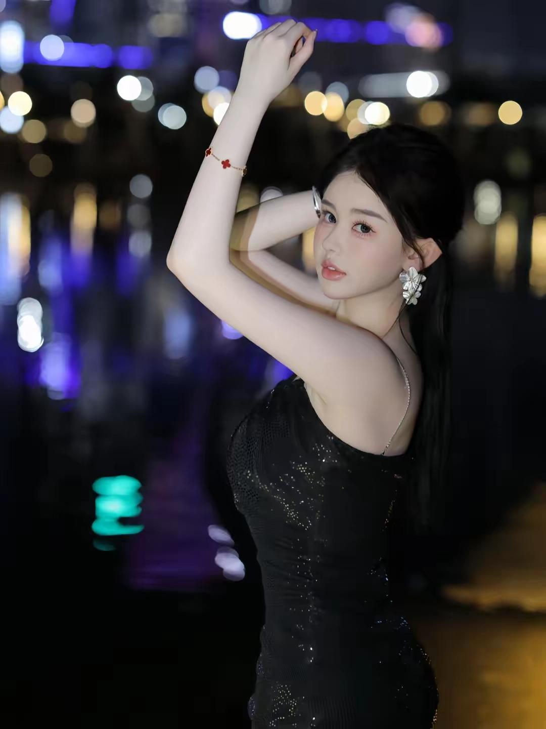 一个穿黑裙的姑娘在夜晚拍照。