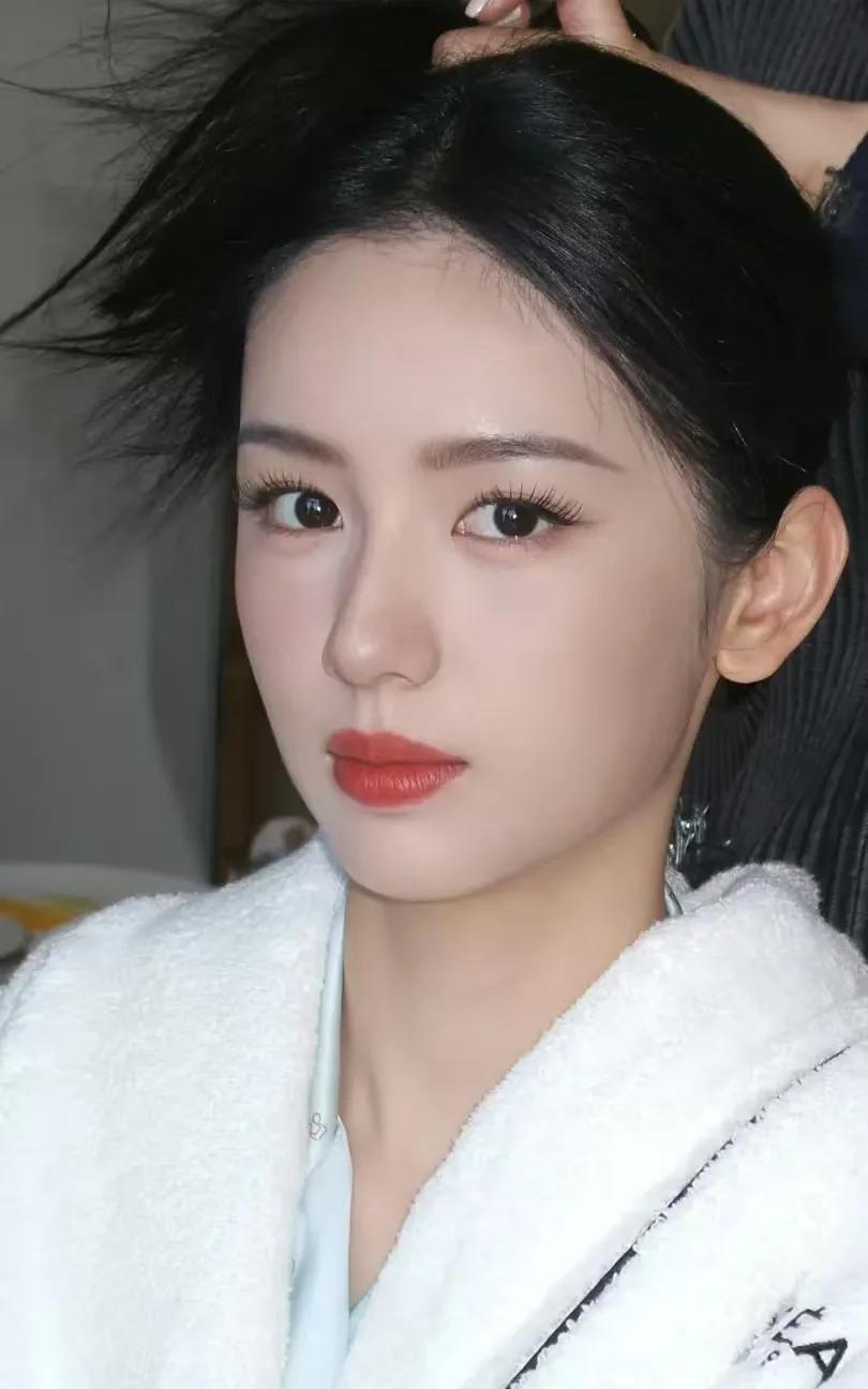 周也她面容精致，眉眼灵动，气质清新又带着一丝甜美。穿一袭白裙现身海外，裙角被海风