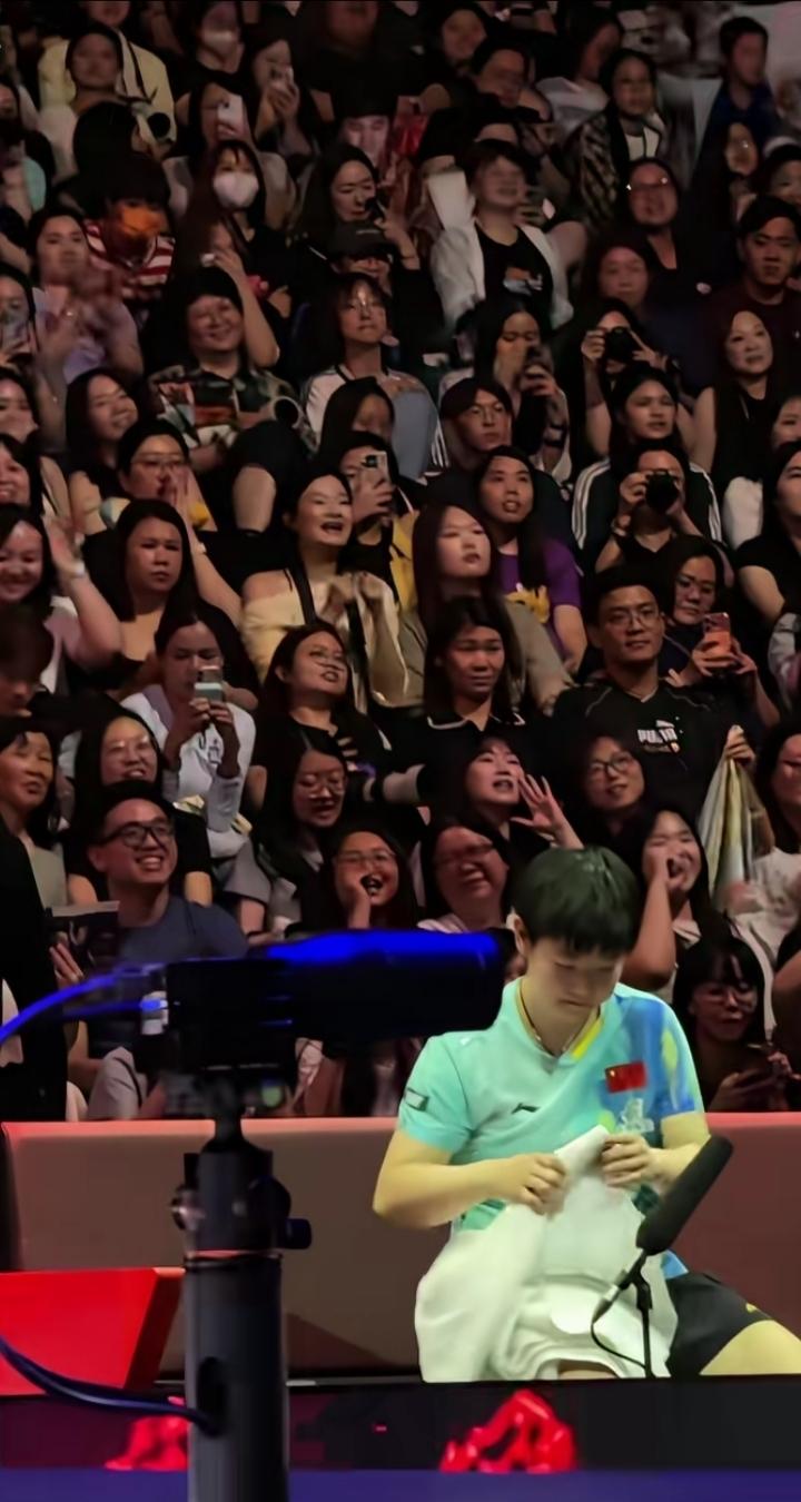 孙颖莎比赛结束后在叠毛巾，她身后观众席上的球迷兄弟姐妹们一直在大声呐喊：“孙颖莎